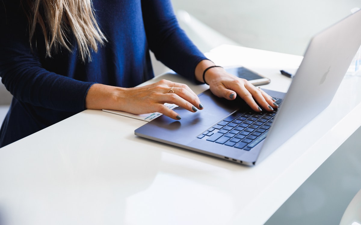 A person reviewing documents with a laptop, notes, and technical diagrams spread out