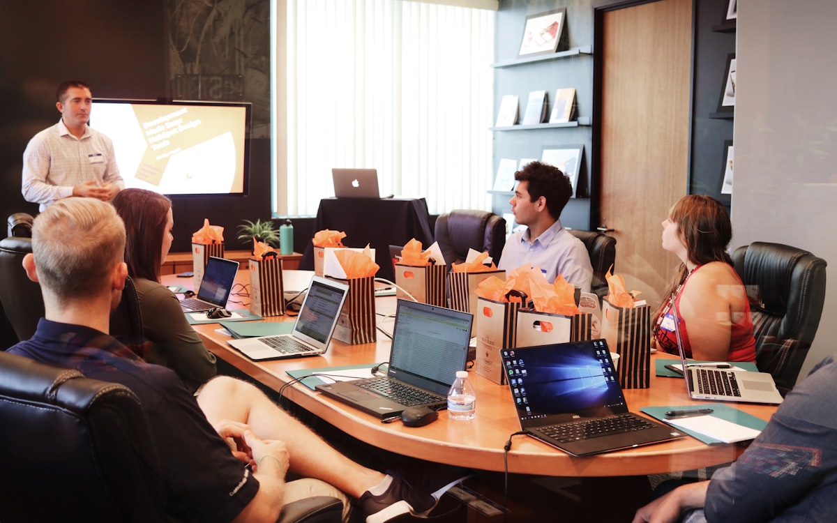 Founders and an advisor around a whiteboard, mid-decision about hiring